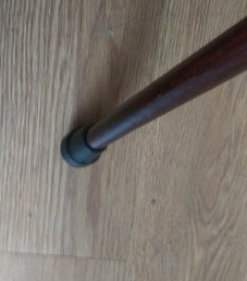 The tip of a wooden cane on the floor